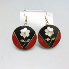 These bold, beautifully made pierced earrings feature the incredible work of the Mexican metalsmiths. They are made of alpaca metal which looks like silver and wears like iron. The metal is an alloy with zinc, copper, tin and sometimes nickel. This pair has a dark crimson red and black enamel background with a white mother of pearl flower. They are in excellent condition and marked ALPACA, Mexico. The earrings are round in shape measuring just about 2 3/8th inches high including the French hook Silver Flower-shaped Brass Earrings, Silver Pierced Brass Flower Earrings, Silver Pierced Flower Earrings In Brass, Silver Brass Flower Earrings, Pierced, Silver Flower Earrings In Brass, Handmade Enamel Flower Shaped Earrings, Handmade Metal Flower Earrings, Silver Enamel Flower Earrings For Pierced Ears, Vintage Black Enamel Earrings For Gifts