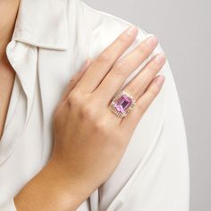 a woman wearing a ring with an amethorate stone in the center and diamonds around it