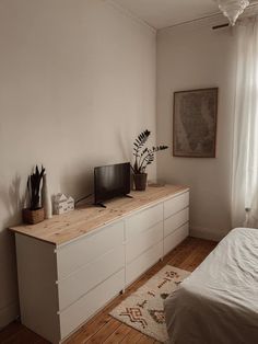 a bed room with a neatly made bed and a flat screen tv on top of a dresser