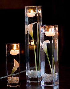 three vases with flowers and candles in them