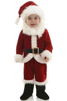 a little boy dressed in a santa suit and holding his hand out to the side