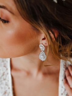 a woman wearing earrings and a white dress