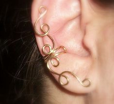 a close up of a person's ear with gold colored wire attached to it