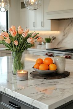 a marble counter top with oranges and candles on it in a white kitchen area