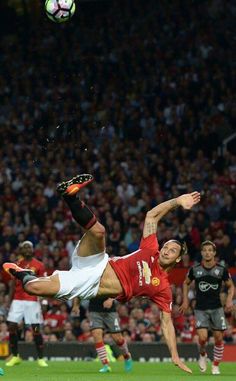 a soccer player is in mid air after hitting the ball with his head while other players look on