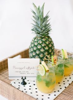 pineapple and apple cocktails on a tray with a place card for the guests