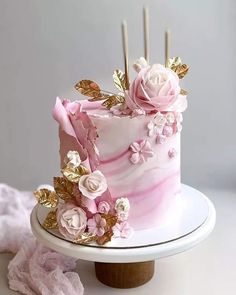 a pink and gold marble cake with flowers on the top is sitting on a white plate