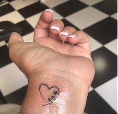 a small heart tattoo on the wrist