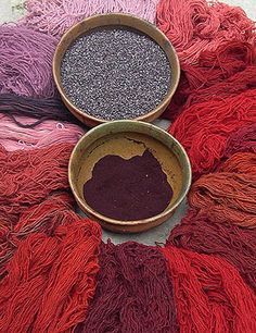 two bowls filled with yarn sitting on top of a floor covered in red and purple colors