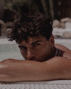 a man laying on top of a white chair next to a swimming pool with water