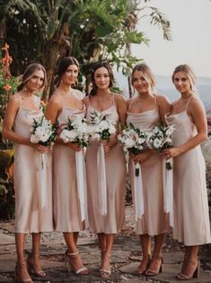 the bridesmaids are all dressed in nude colored dresses with white flowers on their bouquets