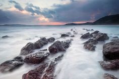 the rocks are covered in water as the sun sets