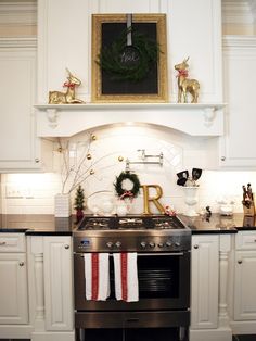 a kitchen with white cabinets and christmas decorations on the counter top, along with an oven