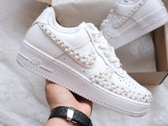 a person is holding a white nike air force with pearls on the top and bottom