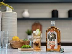 a bottle of alcohol sitting on top of a counter next to some glasses and bottles