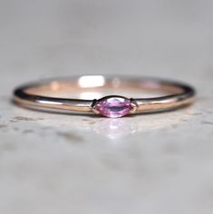 A dainty marquise pink sapphire is at the center of our "Wink" ring, giving you just a little wink of sparkle!   - Marquise stone measures 4mm x 2mm - Handcrafted out of solid 10K or 14K gold - Round band measures 1.2mm in width Processing Times -  Current processing time is 1 - 3 weeks.  Each Item is handmade to order with love and care! In Stock Items -  Contact Liesel Love with any rush order questions, or to see if we have anything ready made and in stock.  Returns -  Liesel Love does take r Fine Jewelry Marquise Pink Gemstone, Gift Marquise Sapphire Ring, Marquise Sapphire Ring As Gift, Pink Marquise Gemstone Jewelry, Pink Marquise Jewelry For Anniversary, Marquise Gemstone Stackable Promise Rings, Fine Jewelry Pink Marquise Ruby Ring, Pink Marquise Ruby Ring Fine Jewelry, Pink Marquise Ring For Anniversary