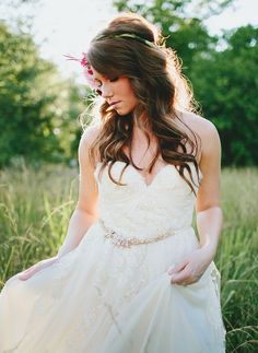 a woman in a white dress standing in tall grass with her hands on her hips