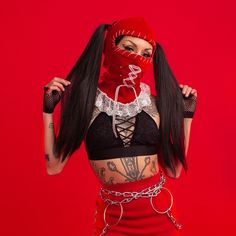 a woman with long hair wearing a red mask and chain around her neck, on a red background