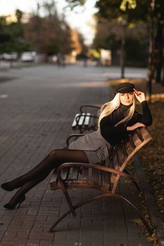 a woman sitting on top of a wooden bench