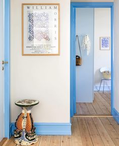 a blue and white hallway with an art piece on the wall