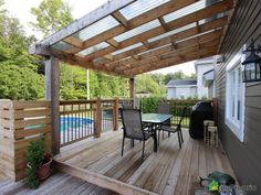 a wooden deck with table and chairs next to a swimming pool