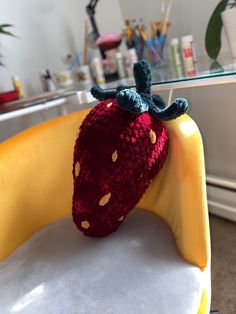 a crocheted strawberry sitting on top of a yellow chair in front of a mirror