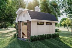 a small white shed sitting on top of a lush green field