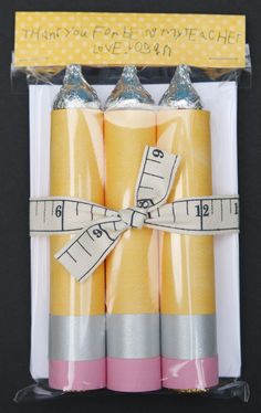 three yellow and silver candles wrapped in plastic wrappers with a ribbon on the top