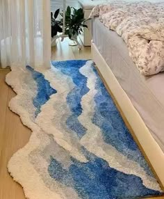 a blue and white rug on the floor next to a bed