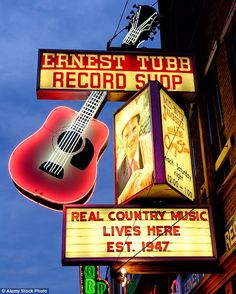 a neon sign for a record shop with a guitar hanging from it's side