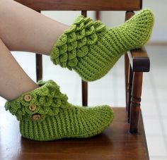 a woman's legs in green knitted slippers sitting on a wooden chair