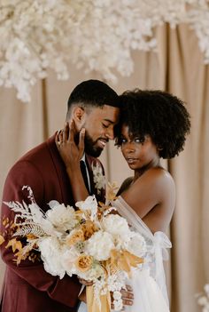 a bride and groom embracing each other in front of a floral tree with white flowers