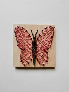 a string art butterfly on a wooden block