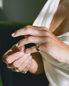 a woman in a white dress is holding onto her wedding band with two gold rings