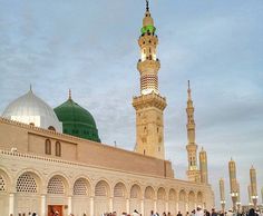 many people are standing in front of a large building with two green and white domes