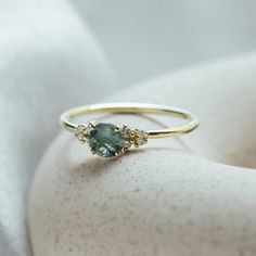 a close up of a ring with a stone on the top and two diamonds on the bottom