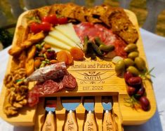 a wooden cutting board with cheese, meats and vegetables on it that is engraved with the name amelie and patrick