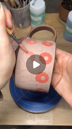 a person is painting a bag on a plate with paintbrushes in their hands