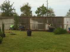 two men are working in the yard with gardening equipment and trash cans on the grass