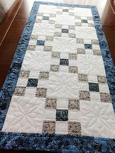 a blue and white quilted table runner on top of a wooden floor next to a window