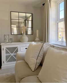 a living room filled with furniture and a large mirror on the wall above it's windows