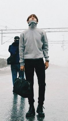 a man is standing in the rain with his eyes closed and people are walking behind him