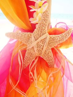 a starfish is tied to the side of a colorful dress at the beach with flowers on it