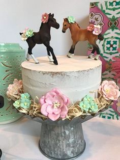 there is a cake that has two horses on top of it and flowers in the middle