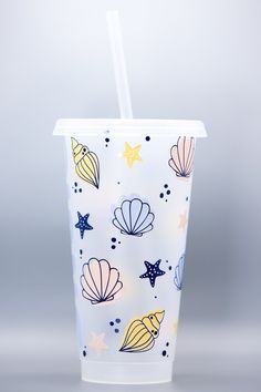 a plastic cup with a straw in the shape of seashells and starfish