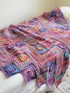 a crocheted blanket sitting on top of a bed