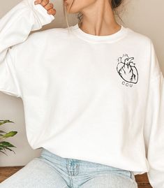 "Calling all cardiac healthcare providers and nurses This sweatshirt is for you or someone you know! This realistic heart is placed perfectly on the left side of your chest! This is a perfect gift for yourself or any healthcare worker you know! This unisex heavy blend crewneck is made of polyester and cotton to provide a comfortable and cozy feel. The collar is ribbed knit and retains its shape after every wash. WHAT IT SAYS: CCU ITEM DETAILS: -50% cotton, 50% polyester -Medium-heavy fabric -Loo Ccu Nurse Shirt, Telemetry Nursing, Realistic Heart, Cardiac Nurse, Medical Scrubs Outfit, Cardiac Nursing, Scrubs Outfit, Hijab Fashionista, Nurse Sweatshirt