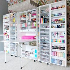 an organized craft room with white shelving and lots of crafting supplies on wheels