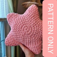 a pink knitted star pillow sitting on top of a window sill with the words pattern only written across it