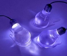 three light bulbs sitting next to each other on top of a white table with purple lighting